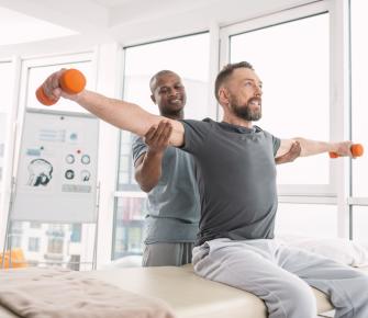 Physical therapist helping patient lift weights